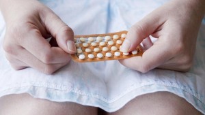 Young woman holding "the pill" on her lap
